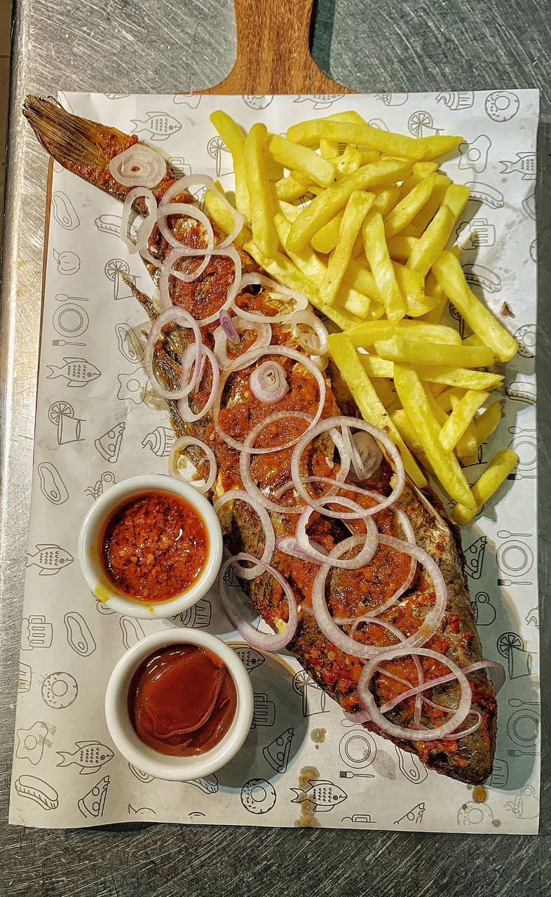 Whole fried fish with onions, chips, and pepper sauce